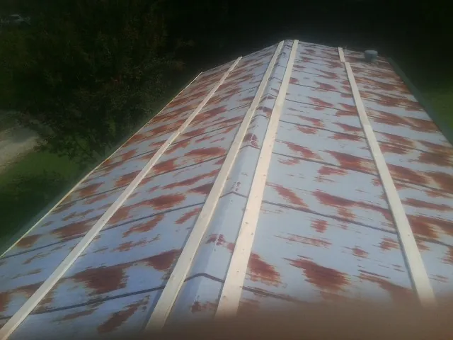 Rusted metal roof panels with new wood purlins before replacement — Storm Damage Roof Repair in Green Lane by Roofing Brothers