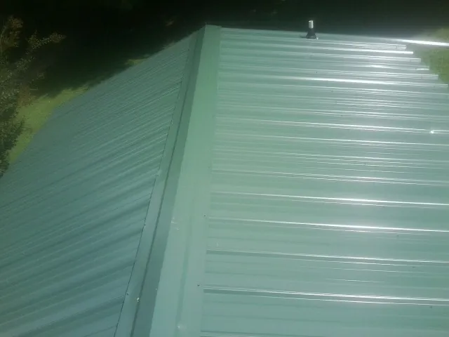 New green metal panels meeting at the ridge of a roof — Flat Roof Repair work by our crew in Green Lane