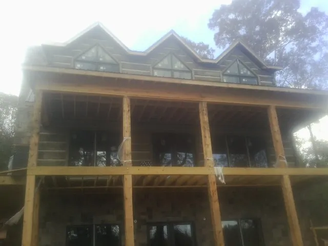 Dormers and porch framing on a large log home under construction — Roof Coating work by our crew in Green Lane