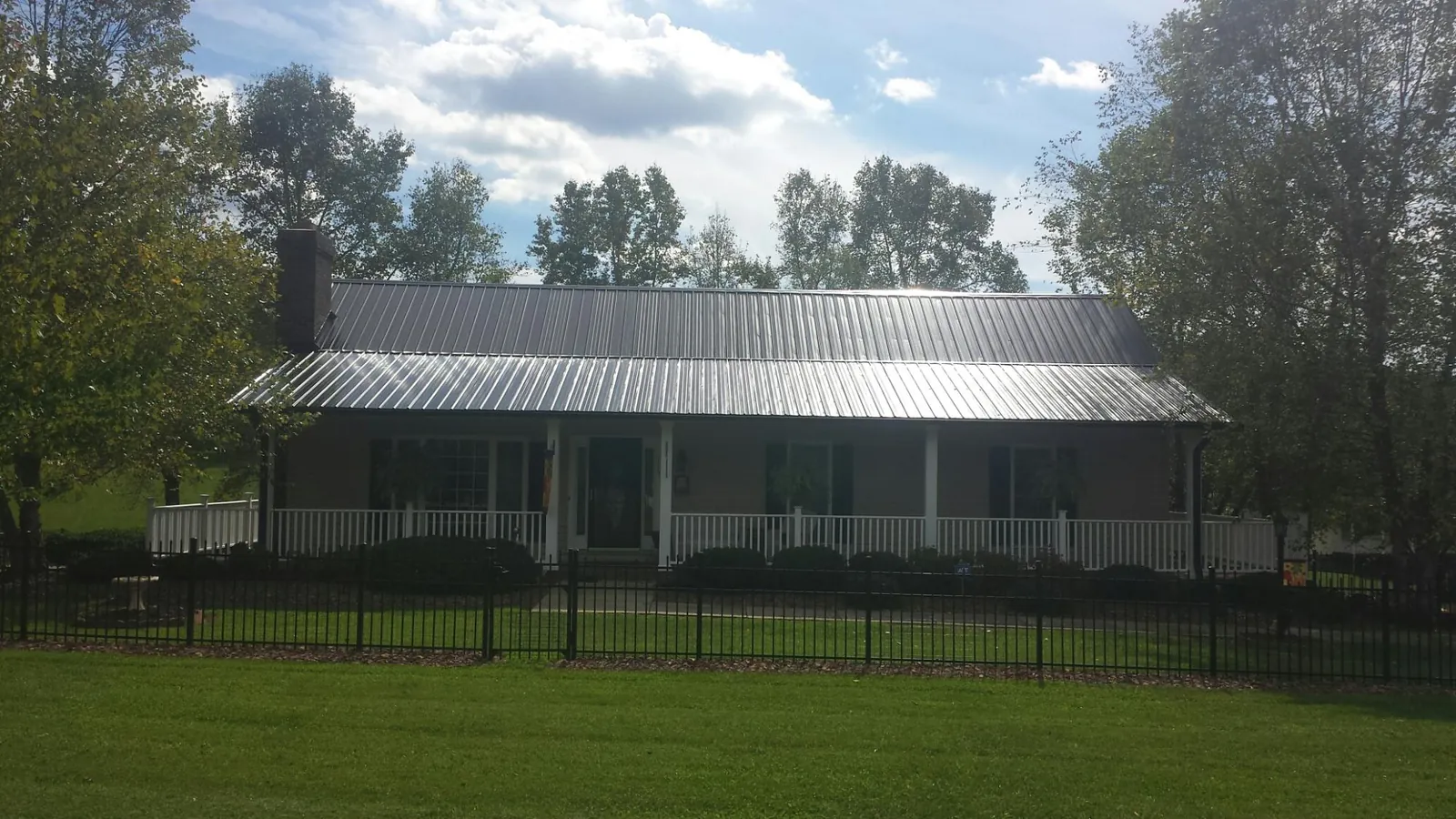 Gray metal roof on a brick ranch with a full width front porch — Gutter Guard Installation work by our crew in Green Lane