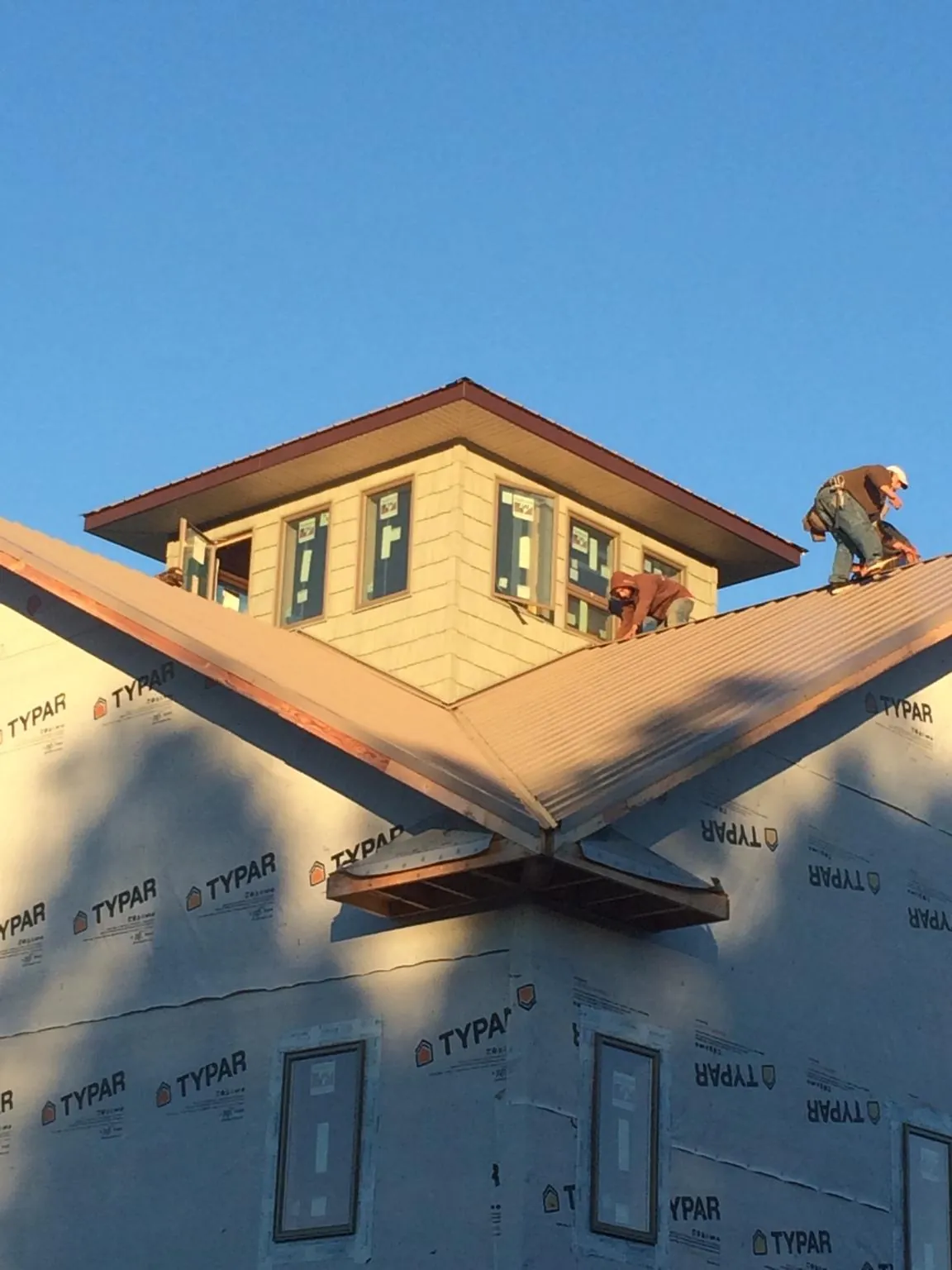 Roofers working around a rooftop cupola on a new metal roof at sunset — Roof Waterproofing in Green Lane by Roofing Brothers